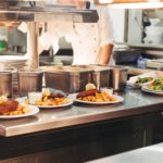 Food orders on the kitchen table in the restaurant, chief decorating schnitzel and fried potatoes, traditional German plate.