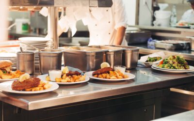 Food orders on the kitchen table in the restaurant, chief decorating schnitzel and fried potatoes, traditional German plate.