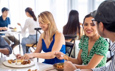 Group of diverse friend talking and eating food together in restaurant.
